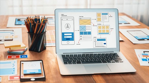 UX wireframes and prototypes on a laptop at a design desk